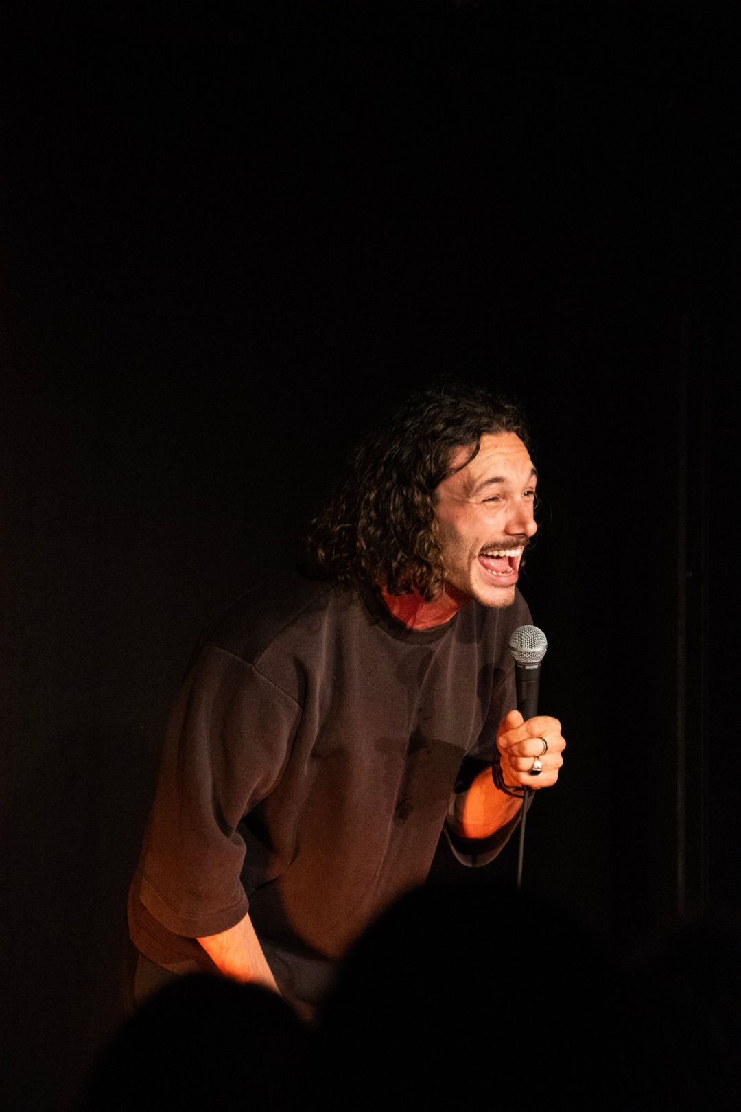 Enzo Ricci éclate de rire sur la scène de L'Estrade, micro en main